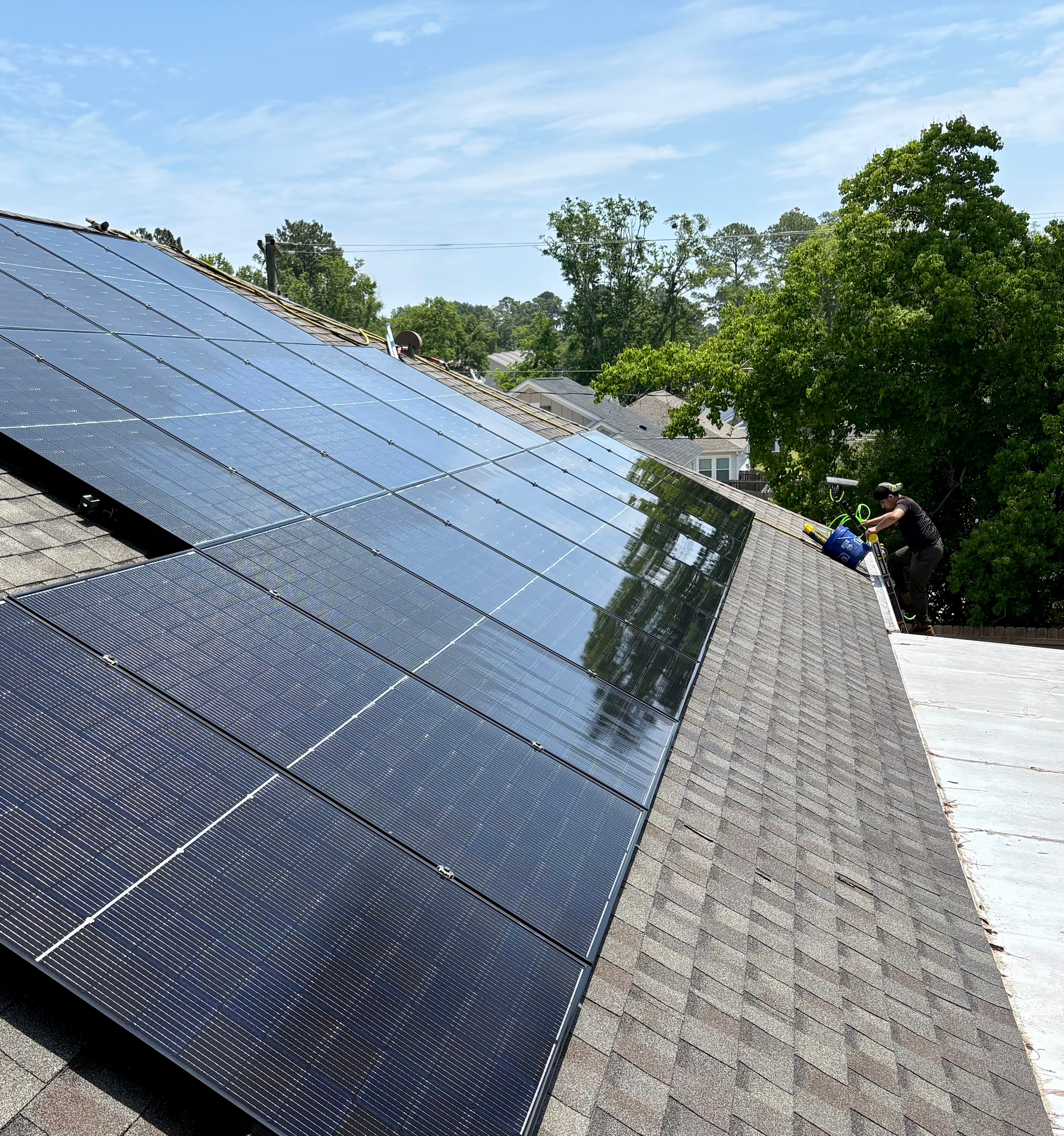 Professional technician cleaning solar panels on residential roofties